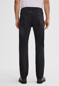 Jeans in denim nero con taglio dritto, cinque tasche e una finitura testurizzata. Presentano una cintura nera e dettagli di cucitura sottili.