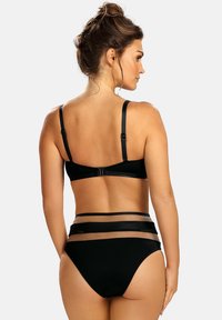 Czarny zestaw bikini z teksturowanej tkaniny. Góra ma regulowane ramiączka i zapięcie na hak, podczas gdy dół posiada przezroczyste paski akcentujące.