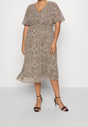 Robe midi à motifs marron et beige avec un col en V, des manches courtes et un design portefeuille. Tissu lisse et silhouette fluide. Talons noirs à bride à la cheville.