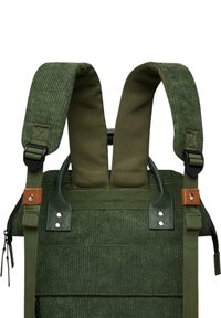 Spalline verdi con texture a righe, attaccate a una robusta borsa in tessuto. Presenta dettagli in pelle e hardware metallico.