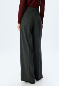 Brede pijpen in donkergrijs stof met een gestructureerde afwerking, voorzien van een hoge taille en subtiele plooien, geschikt voor formele kleding.