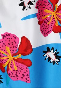 Impression de tissu floral lumineux avec de grandes fleurs roses et rouges, des étamines jaunes, des pétales tachetés de noir et des formes abstraites bleu et blanc en arrière-plan.