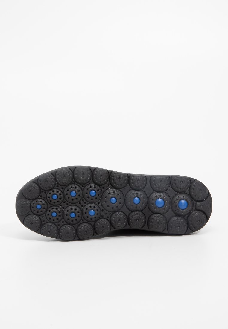 Schwarze Schuhsohle mit abgerundeten, strukturierten Grip-Pads mit blauen Akzenten und Perforationen für besseren Halt. Glatte Kanten mit einem geschwungenen Design.