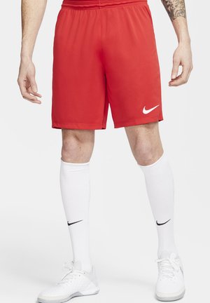 Rote Nike Sportshorts mit einem elastischen Bund und einem weißen Nike-Logo. Getragen mit weißen Kniestrümpfen und weißen Sportschuhen.