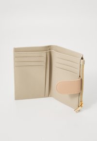 Beige lommebok med glidelås, flere kortrom og trykknapp. Glatt tekstur med kontrasterende lysebrune detaljer.