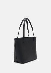 Musta nahkainen kassi, jossa on sileä pinta, suorakulmainen muoto ja kaksi pitkää kahvaa. Minimalistinen muotoilu ilman näkyvää metallia tai kuvioita.