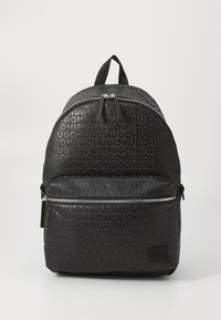 Mochila negra con patrón de logotipo en relieve "HUGO", forma redondeada, textura suave, compartimentos con doble cremallera y un asa en la parte superior para llevar.