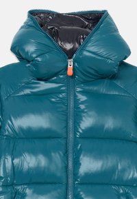 Teal puffjacka med hög krage, glänsande yta, framdragkedja med orange dragtag och kviltad design. Inre foder i mörk färg.