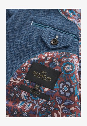 Sininen herringbone-takkinen takki, jossa on kuviollinen burgundinpunainen vuori. Mukana musta nappi, koko 40R tarrat ja "Slim Fit" -suunnittelu.