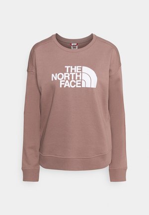 Sweatshirt mauve à col rond avec manches longues et logo blanc "THE NORTH FACE" centré sur la poitrine.