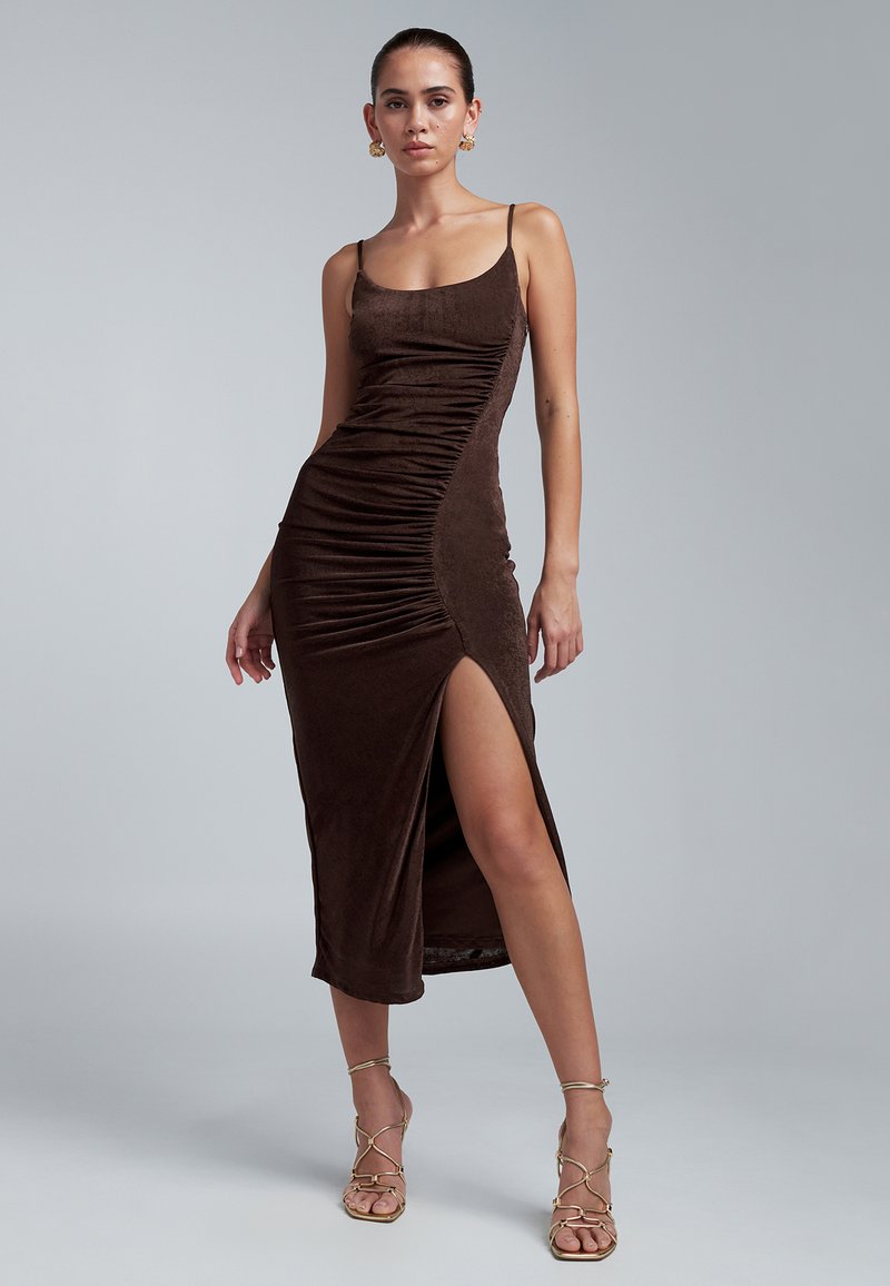 Robe midi ajustée marron avec fronces sur les côtés, fines bretelles et une fente haute. Confectionnée dans un tissu doux et texturé.