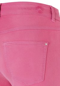 Jean en denim rose avec une seule poche arrière, des coutures nettes et une texture lisse. Logo embossé sur la ceinture. Coupe taille mi-haute.