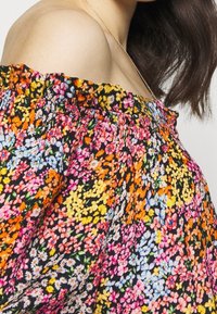 Off-the-shoulder blouse van zwarte stof met kleurrijke bloemenpatronen, met een elastische halslijn en een gestructureerd materiaal.