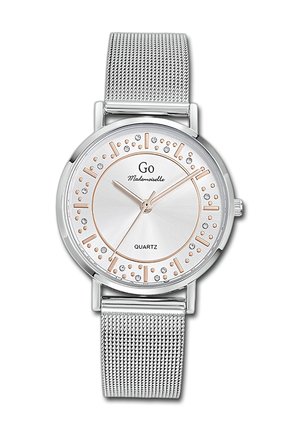 Montre en quartz argentée avec un bracelet en mailles métalliques. Le cadran rond présente un fond argent clair avec des accents en rose doré et des cristaux décoratifs.