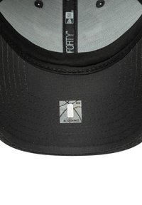 Schwarze Kappe mit einem gewölbten Schirm, ausgestattet mit einer strukturierten Oberfläche und einem glänzenden Etikett mit einem einzigartigen Logo auf der Unterseite.