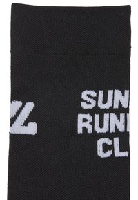 Czarna skarpeta z białym napisem "SUN RUNNING CL" w pogrubionej, blokowej czcionce. Skarpeta ma bezszwową konstrukcję i teksturowaną tkaninę.