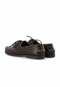 Chaussures bateau en cuir marron avec semelles noires, coutures blanches et lacets noués sur fond blanc, vues de dos et de côté.