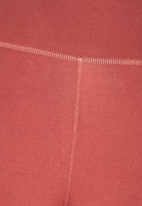 Leggings taille haute en tissu rose poussiéreux texturé avec des coutures plates et une finition lisse, conçus pour le confort et la flexibilité.