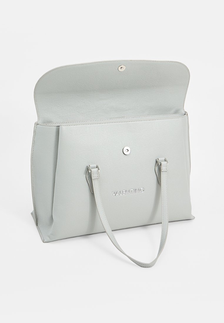 Sac à main Valentino gris clair avec surface texturée, rabat ouvert, deux poignées et fermeture à pression magnétique sur fond blanc.