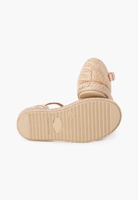 Austo pintinis espadrilas su tekstūruotu audinio viršumi, kulkšnies dirželiu ir banguotu guminėmis padais. Yra siuvinėtos detalės ir mažas sagtis.