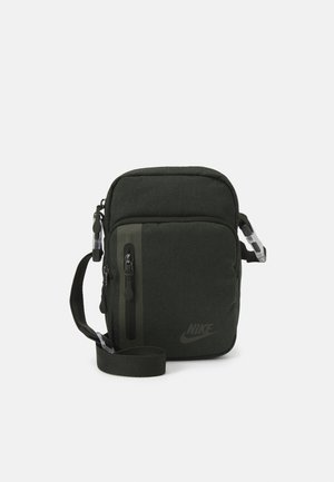 Bolso de nylon verde cruzado con correa ajustable, cremalleras frontales y un logo en el lateral. Presenta una textura sólida y forma rectangular.