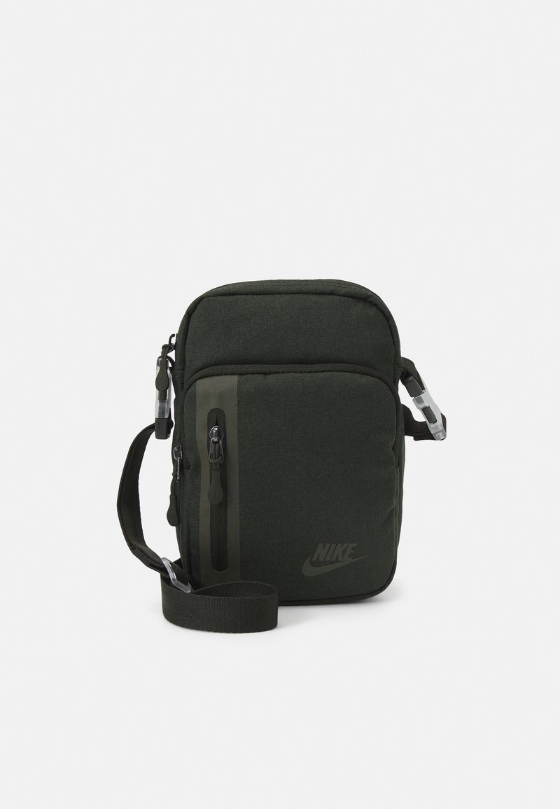 Sac bandoulière en nylon vert avec une sangle réglable, fermetures éclair à l'avant et un logo sur le côté. Présente une texture solide et une forme rectangulaire.