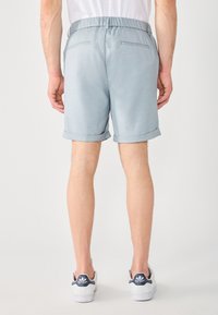 Pantaloni corti azzurri, a lunghezza ginocchio, con cintura elastica, orlo risvoltato e due tasche posteriori. Realizzati in un tessuto testurizzato.