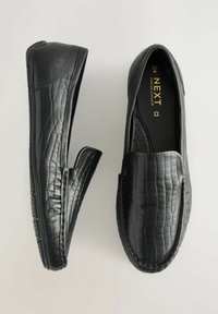 Mocassins noirs en cuir texturé avec un motif crocodile. Dotés d'un design sans lacets et d'un détail perforé sur les semelles intérieures.