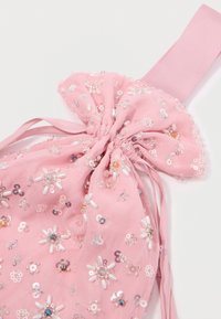 Tecido de chiffon rosa com decoração de pérolas florais e um detalhe de laço amarrado. Apresenta vários acabamentos iridescentes e pastéis.