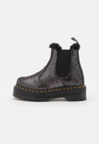Black and silver chelsea boots with a textured upper, featuring a fluffy trim, elastic side panels, and yellow stitching on a thick sole.
