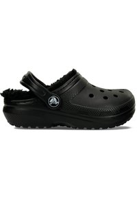 Sabots noirs à surface texturée, perforations pour la respirabilité et une doublure en fourrure noire douce. Équipés d'une bride arrière pour un maintien sûr.