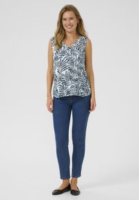 Top sans manches à motif floral dans des tons de bleu clair et noir, associé à un jean skinny bleu foncé et des ballerines noires. Design simple et décontracté.