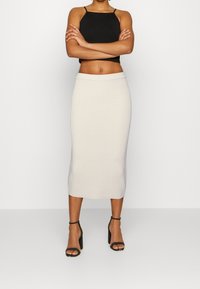 Svart crop top med tunna band, tillsammans med en off-white ribbad midikjol. Har en åtsittande design och slät textur. Svarta klacksandaler med blockklack.