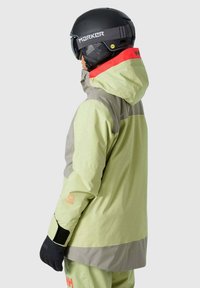Hellgrüne Skijacke mit grauen Akzenten, wasserdichtem Material, verstellbarer Kapuze und schwarzen Handschuhen. Enthält Logo-Details auf dem Ärmel.