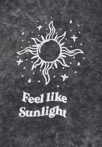 Soleil blanc avec des rayons et des étoiles au-dessus de la phrase "Feel like Sunlight" imprimée sur un tissu texturé gris foncé.
