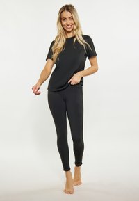 Costum athletic negru format dintr-un top cu mânecă scurtă și colanți ajustați, fabricat dintr-un material neted și elastic. Prezintă o siluetă aerodinamică.
