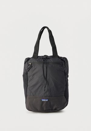 Bolso tote negro de Patagonia con asas dobles, bolsillo frontal con cremallera y cierre de cordón en el compartimento principal.