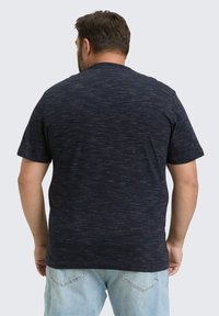 Kurzärmliges, marineblaues T-Shirt mit einem strukturierten, marmorierten Muster. Klassisches Rundhalsdesign, kombiniert mit hellblauen Jeans.