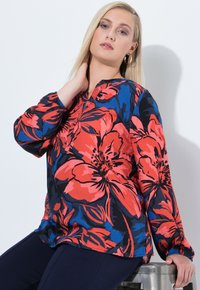 Camicia a maniche lunghe con una stampa floreale rossa e blu su sfondo nero; presenta un collo rotondo e un tessuto morbido e fluente.