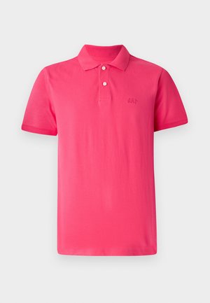 Svetlo roza polo majica iz bombaža, ki ima klasičen ovratnik, tri gumbe in izvezen logo 'GAP' na prsih.