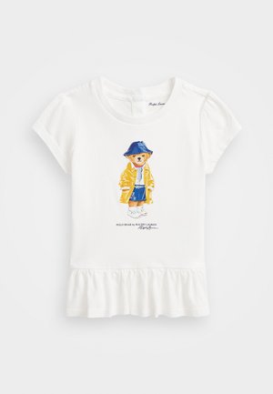 Cămașă albă din bumbac, cu un imprimeu reprezentând un urs de desen animat îmbrăcat într-o pelerină galbenă și o șapcă albastră, având un tiv cu volane la bază.