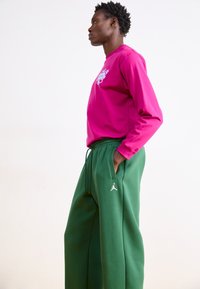 Roze longsleeve shirt met logo en groene sweatpants met een trekkoord en zijzakken, gemaakt van zachte, gestructureerde stof.