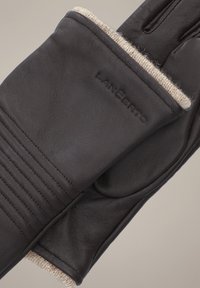 Ciemnobrązowe skórzane rękawice mają teksturowane wykończenie, żebrowane akcenty oraz beżowe futerko w mankiecie, z marką wtopioną w powierzchnię.