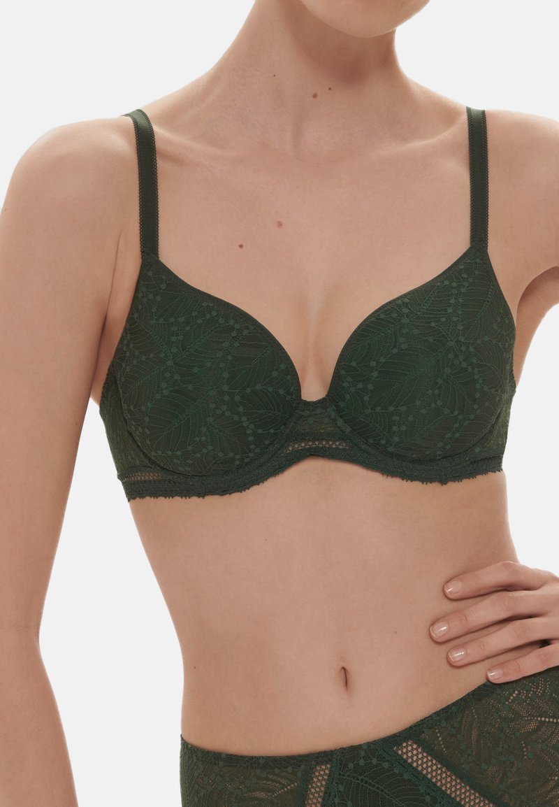 Dark green lace bra with underwire and molded cups, featuring floral patterns and scalloped edges. Adjustable straps for fit.