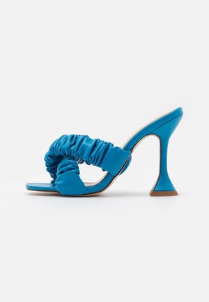 Niebieskie sandały na obcasie z marszczonym syntetycznym wierzchem, kwadratowym noskiem i charakterystycznym rozszerzanym obcasem. Gładka tekstura i minimalistyczny design.