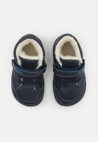 Laivansiniset taaperoiden kengät, jotka on valmistettu nahasta ja joissa on pehmeä shearling-vuori. Kenkäparissa on tarranauhat ja koristeompeleet sivuilla.