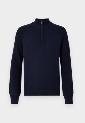 Tamsiai mėlynas megztinis su aukštu apykakle ir pusiau užtrauktuku, su gumeriais ant rankovių ir iškirpės.