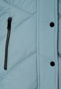 Lichtblauwe gestikte jas met een slank ontwerp, voorzien van een zwarte ritszak en zwarte drukknoopjes, benadrukt door diagonale stiksels en een gladde textuur.