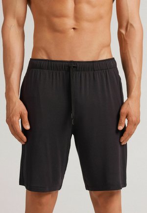 Shorts de sport noirs avec une taille élastique et un cordon de serrage. Tissu lisse, longueur genoux, avec des poches latérales et un design simple.