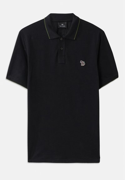 Melna pūļa krekls, izgatavots no kokvilnas, ar zaļu apkakles apdari. Kreklam ir neliela daudzkrāsaina ziloņa izšuvuma uz kreisā krūšu.